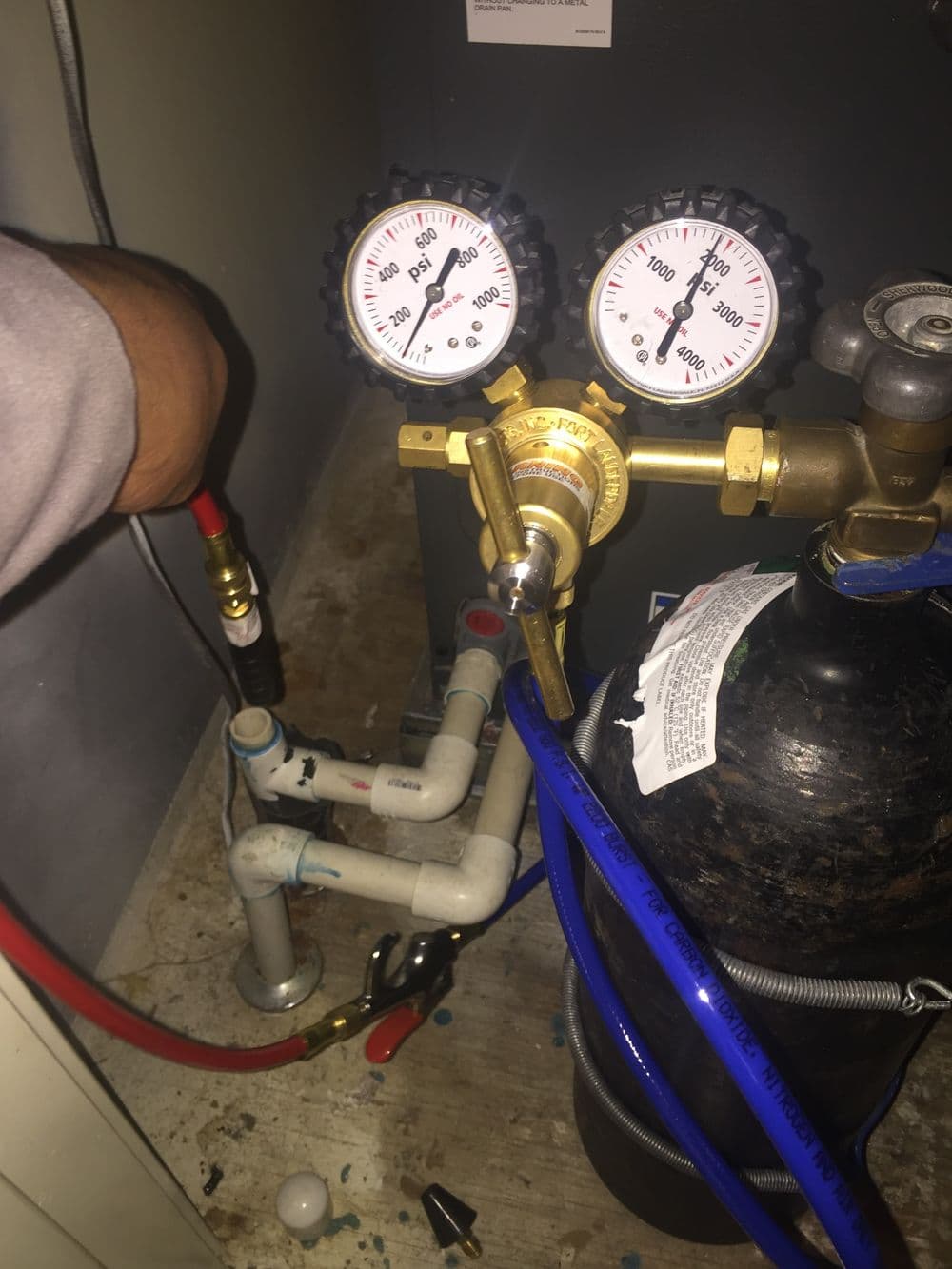 HVAC technician using pressure gauges on a refrigerant system for maintenance.